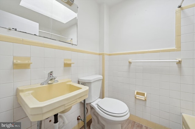 bathroom with hardwood / wood-style floors, sink, toilet, and tile walls