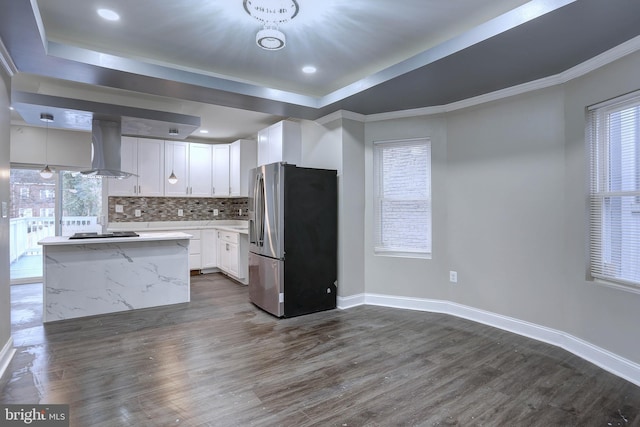 kitchen featuring white cabinets, extractor fan, a kitchen island, dark hardwood / wood-style flooring, and stainless steel refrigerator