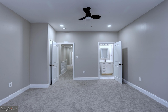 unfurnished bedroom featuring ceiling fan, ensuite bathroom, and light carpet