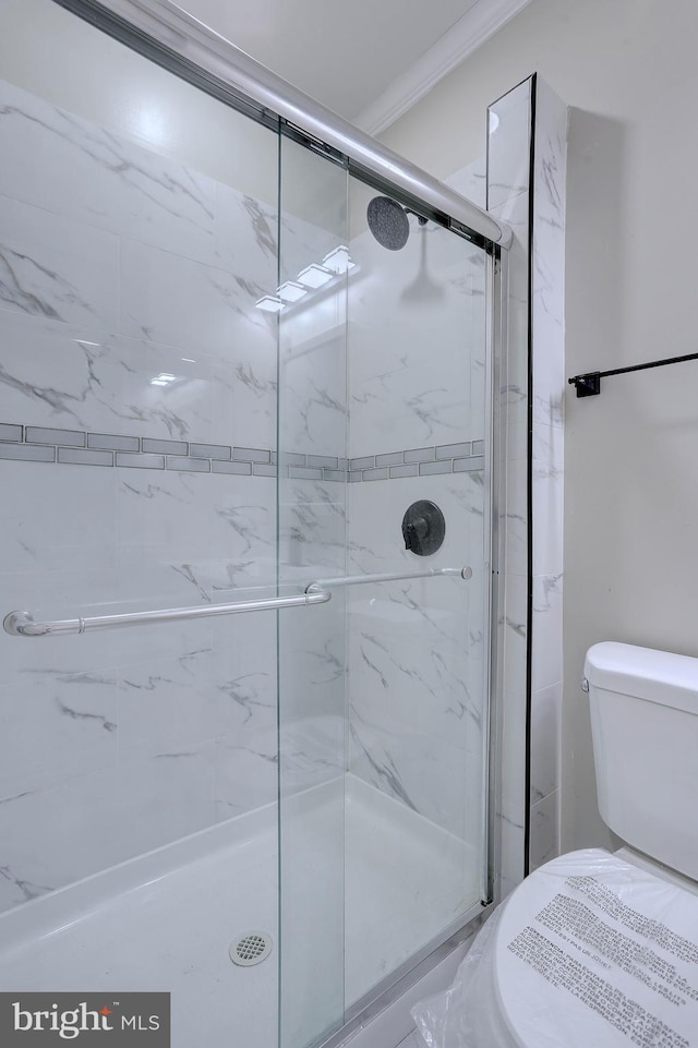 bathroom with an enclosed shower, ornamental molding, and toilet