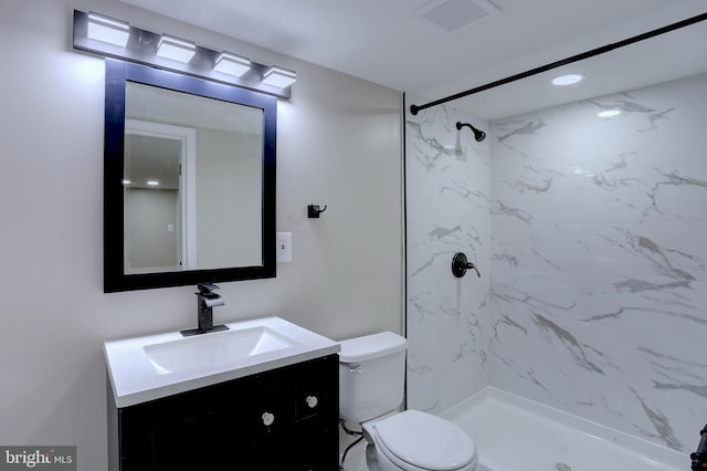 bathroom with toilet, vanity, and tiled shower