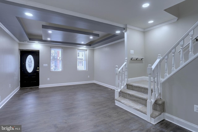 foyer entrance with a raised ceiling, dark wood-type flooring, and ornamental molding