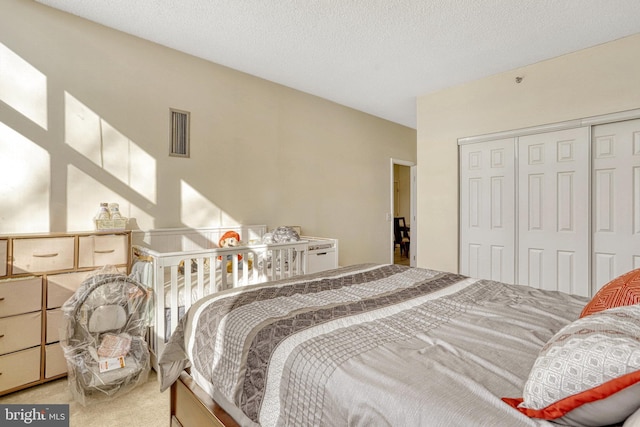 bedroom with a textured ceiling, a closet, and carpet flooring