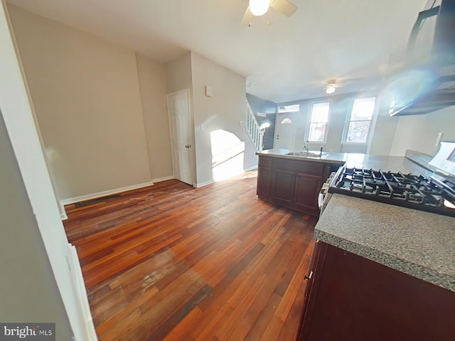 kitchen featuring sink, dark brown cabinets, range with gas stovetop, dark hardwood / wood-style flooring, and exhaust hood