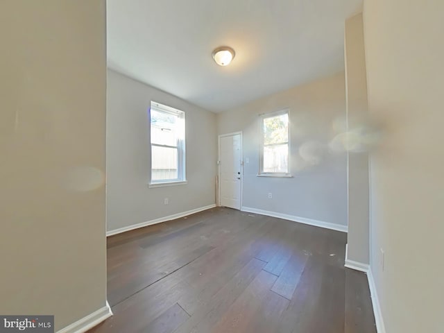 spare room featuring plenty of natural light and dark hardwood / wood-style flooring