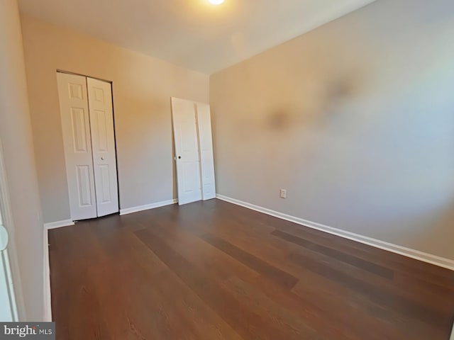 unfurnished bedroom featuring dark wood-type flooring and a closet