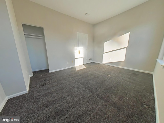 unfurnished bedroom with dark carpet and a closet