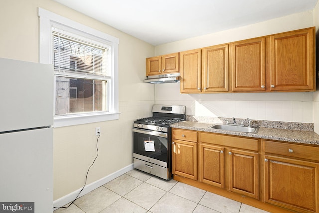 kitchen featuring white refrigerator, light tile patterned flooring, sink, and gas stove