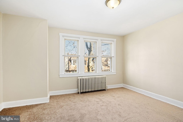 spare room with radiator and light colored carpet