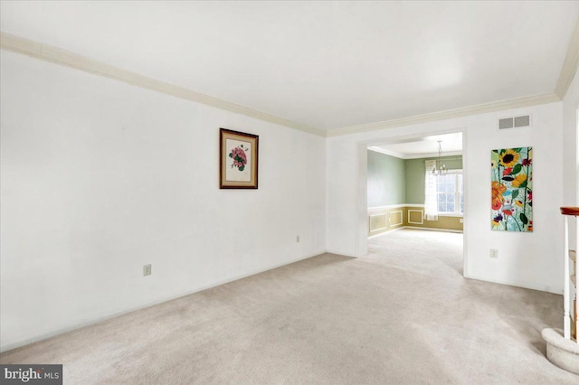 carpeted spare room with ornamental molding and an inviting chandelier