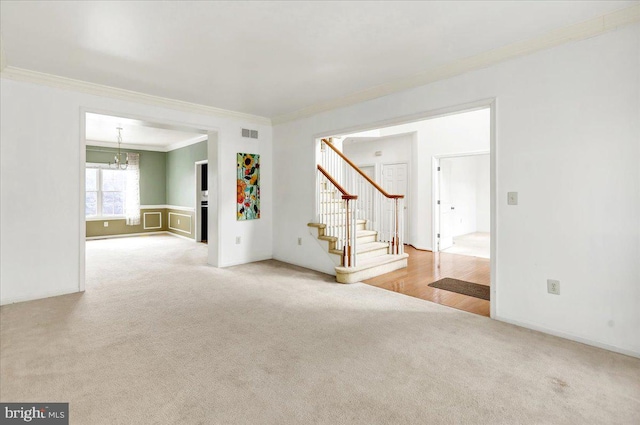 empty room with crown molding, carpet, and an inviting chandelier