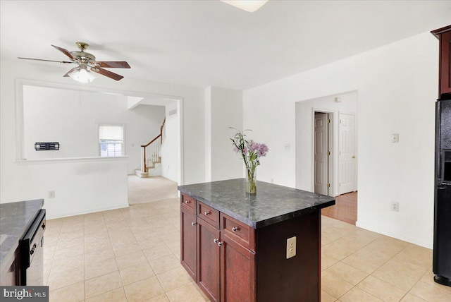 kitchen featuring ceiling fan, black refrigerator, a kitchen island, and light tile patterned floors