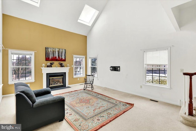 living room with carpet, a skylight, and high vaulted ceiling