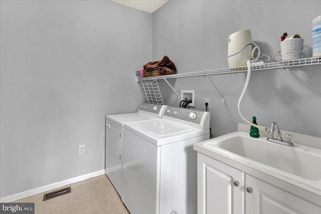 clothes washing area featuring washing machine and dryer, sink, and cabinets