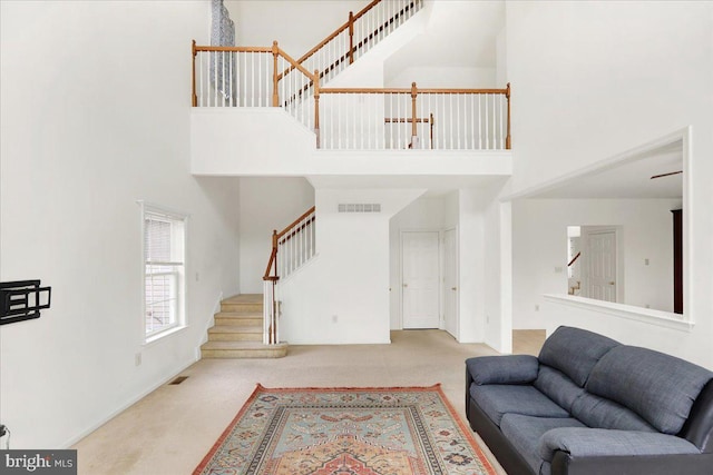 living room featuring a high ceiling and light colored carpet