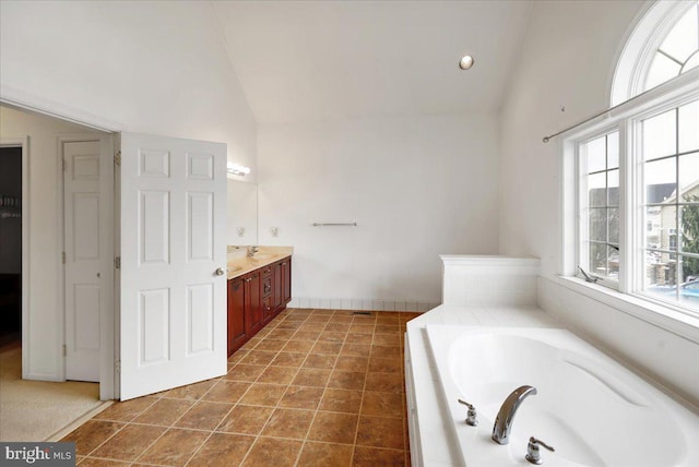 bathroom featuring tile patterned floors, vaulted ceiling, plenty of natural light, and tiled tub