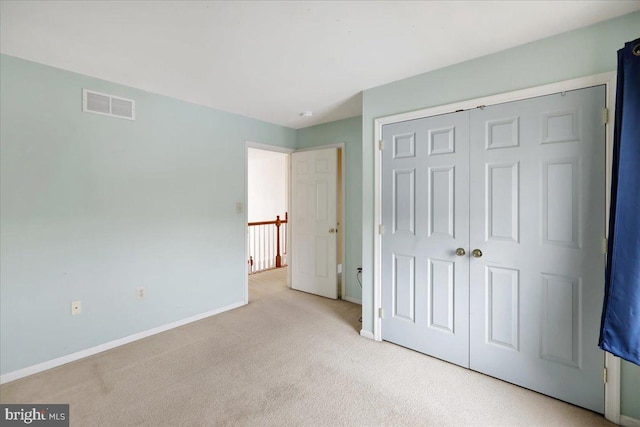 unfurnished bedroom with light colored carpet and a closet