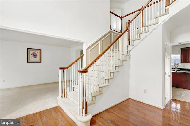 stairs with a high ceiling and hardwood / wood-style flooring