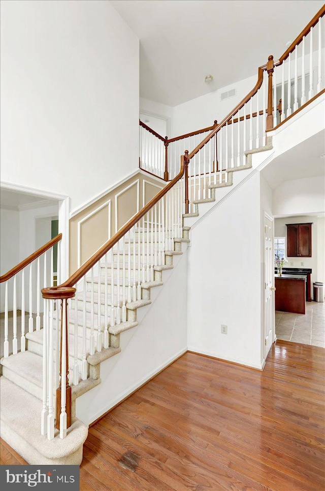 stairs featuring wood-type flooring and a high ceiling