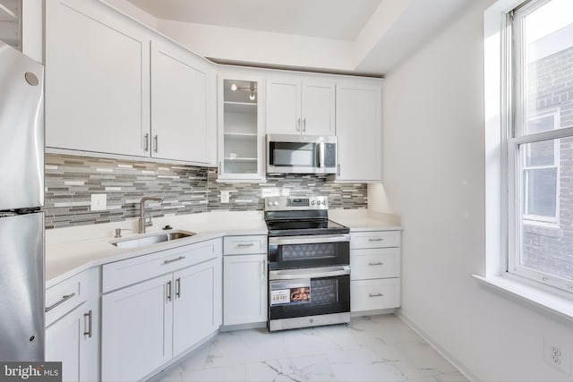 kitchen featuring sink, white cabinets, backsplash, stainless steel appliances, and a healthy amount of sunlight