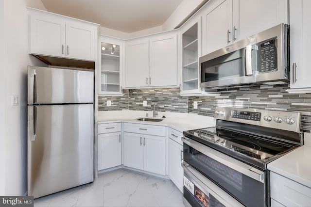 kitchen with sink, decorative backsplash, white cabinets, and appliances with stainless steel finishes