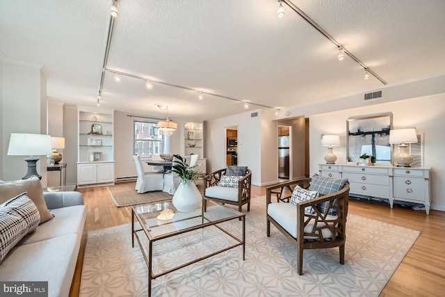 living room featuring a baseboard radiator, rail lighting, a textured ceiling, and light hardwood / wood-style floors