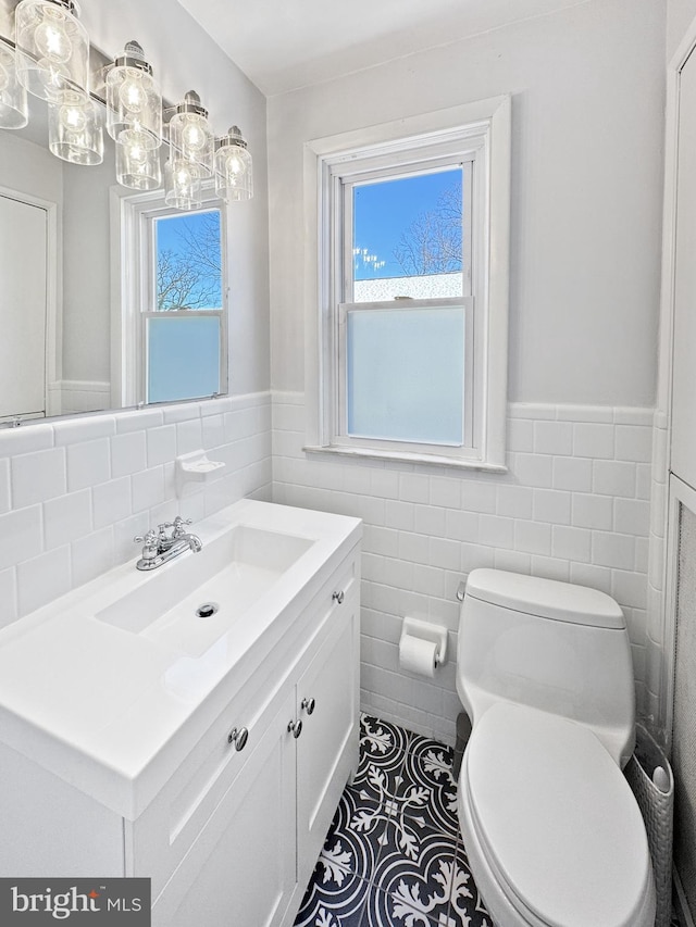 bathroom with tile patterned floors, vanity, toilet, and tile walls