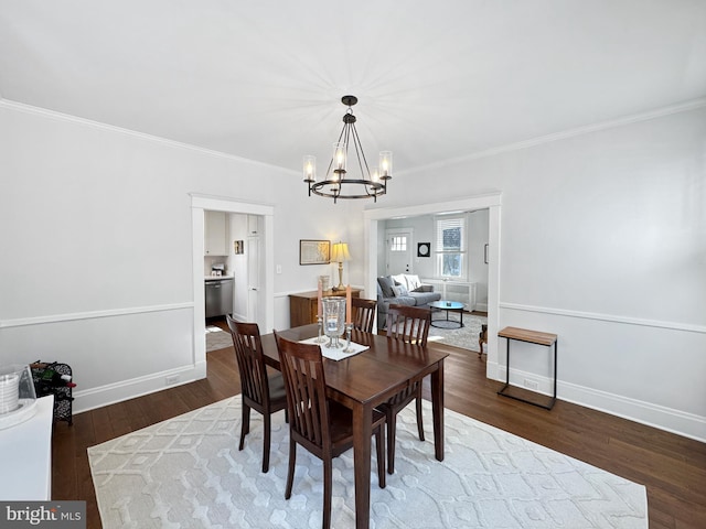 dining area with dark hardwood / wood-style flooring, an inviting chandelier, and crown molding