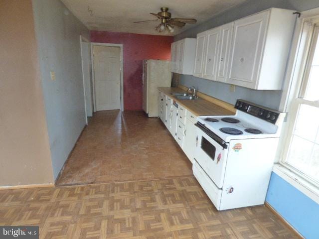 kitchen featuring white range with electric stovetop, white cabinetry, sink, and light parquet floors