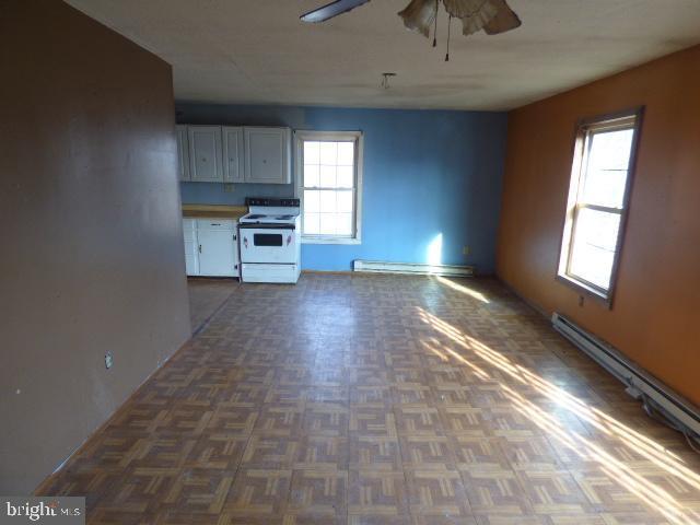 kitchen featuring white cabinetry, dark parquet flooring, electric stove, and a baseboard radiator