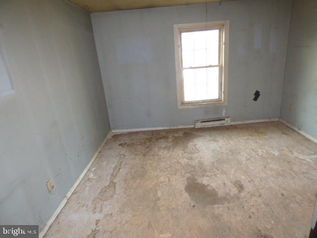 unfurnished room with a baseboard heating unit