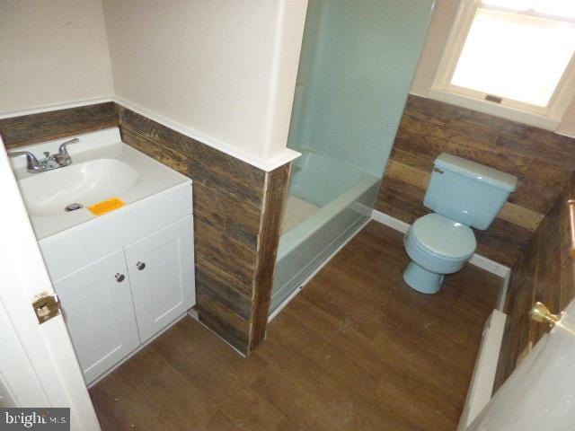 bathroom with hardwood / wood-style flooring, vanity, a bathtub, and toilet