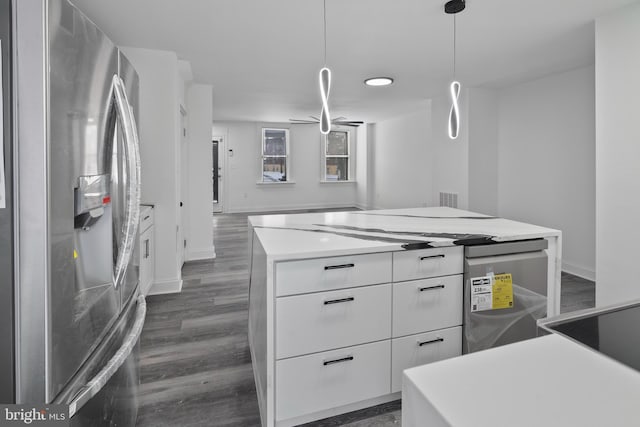 kitchen with white cabinets, stainless steel fridge, a center island, and decorative light fixtures