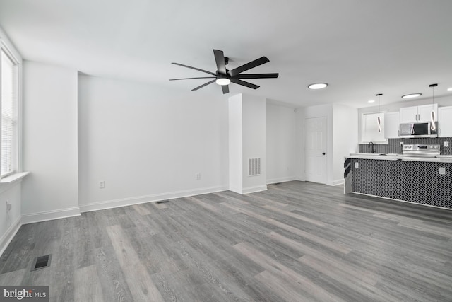 unfurnished living room featuring hardwood / wood-style floors, ceiling fan, and sink