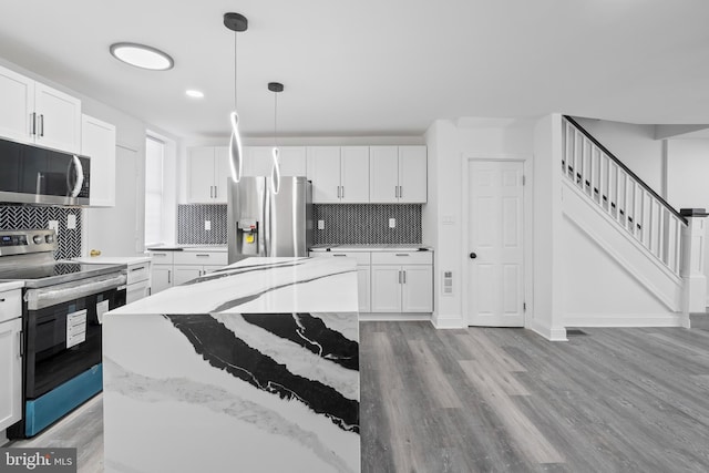 kitchen with a kitchen island, light stone counters, white cabinetry, and stainless steel appliances