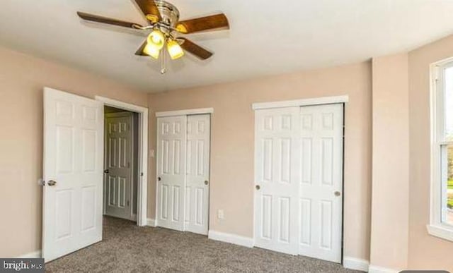 unfurnished bedroom with carpet flooring, multiple windows, ceiling fan, and two closets