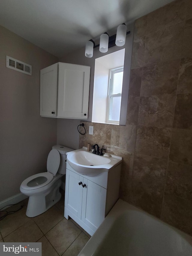 bathroom featuring vanity, backsplash, tile patterned flooring, a washtub, and toilet