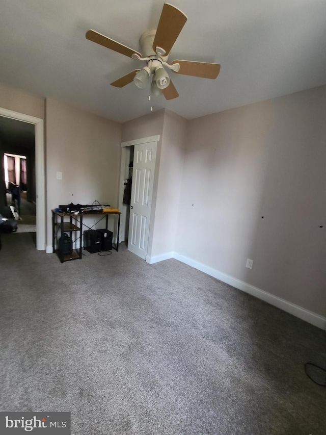 interior space with dark carpet and ceiling fan