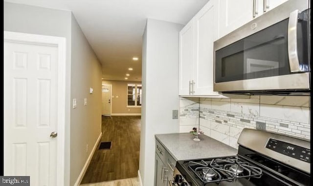 kitchen with decorative backsplash, white cabinetry, light hardwood / wood-style floors, and appliances with stainless steel finishes