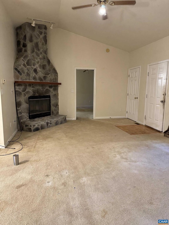 unfurnished living room featuring ceiling fan, a stone fireplace, light colored carpet, and vaulted ceiling