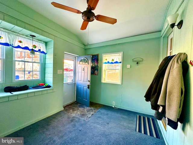 interior space featuring dark colored carpet, vaulted ceiling, and ceiling fan