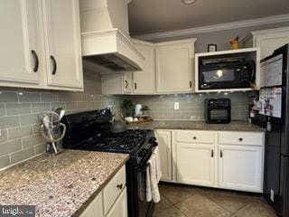 kitchen with custom exhaust hood, black appliances, dark tile patterned floors, tasteful backsplash, and light stone counters