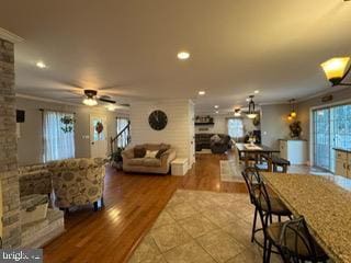 living room with plenty of natural light, ceiling fan, wood-type flooring, and crown molding