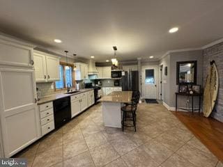 kitchen featuring pendant lighting, a center island, black dishwasher, a kitchen bar, and white cabinetry