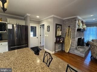 kitchen featuring light stone countertops, white cabinetry, crown molding, and black appliances