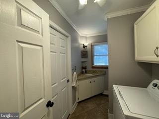 clothes washing area featuring cabinets, ornamental molding, and sink