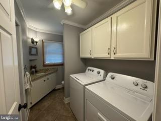 clothes washing area with cabinets, washing machine and dryer, ceiling fan, and crown molding