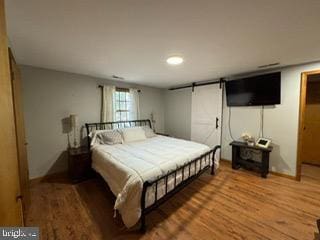 bedroom featuring hardwood / wood-style floors and a barn door