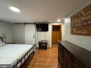 bedroom with a barn door and light hardwood / wood-style flooring