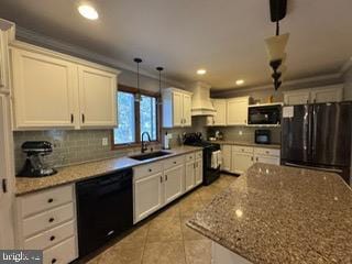 kitchen with black appliances, light stone counters, sink, and hanging light fixtures